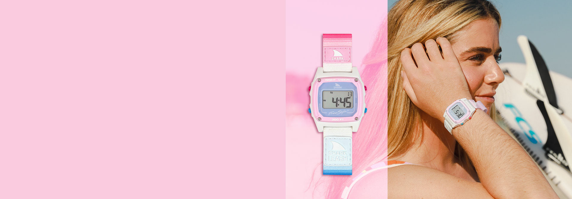 A woman wearing a pink and blue Shark watch, with a surfboard in the background.
