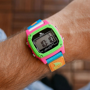 A Freestyle SHARK CLASSIC CLIP BLACK/NEON watch with a colorful band is worn on the wrist, its face showing digits.