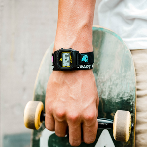 A hand holds a skateboard, wearing the Freestyle SHARK CLASSIC CLIP SINCE 81 PRIMARY BLACK with vibrant graphics.