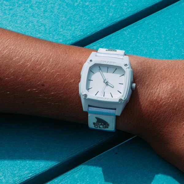 SHARK CLASSIC CLIP watch with sleek design and water-resistant features resting on a turquoise surface.