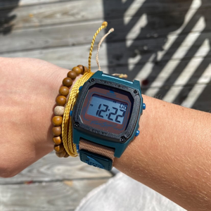 A Freestyle SHARK CLASSIC CLIP SEA N SAND watch, worn with wooden bead and yellow rope bracelets.