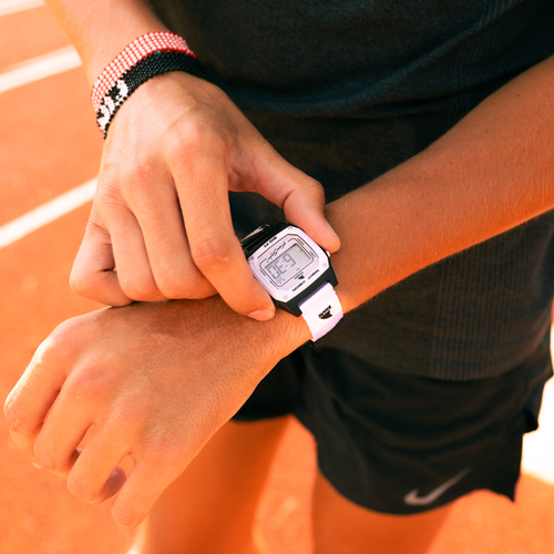 Close-up of a person looking at their Freestyle SHARK CLASSIC LEASH ORCA watch while standing on an outdoor running track.