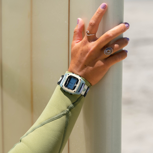 A hand with purple nails wears a Freestyle LUKE DAVIS SIGNATURE SHARK CLASSIC CLIP LUKE THE GREY watch over a green wetsuit.