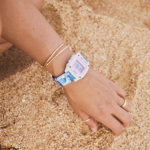 A hand wearing the Freestyle SAGE ERICKSON SIGNATURE SHARK CLASSIC CLIP rests on sand, highlighting Sage Erickson’s distinctive style.