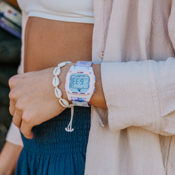 Person wearing a Freestyle Shark Classic Clip watch in periwinkle and a shell bracelet.