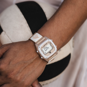 A hand wearing a Freestyle SHARK CLASSIC CLIP PEACH watch rests on a black and white volleyball.