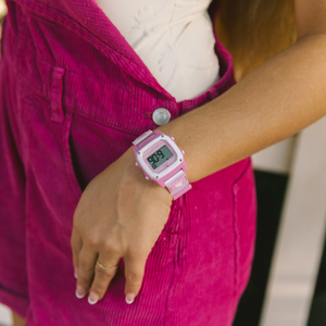 Person wearing a Freestyle SHARK CLASSIC LEASH PINK CRUSH watch with magenta overalls and a white top, hand resting at their side.