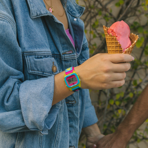 Person in a denim jacket holds a pink ice cream, wearing the Freestyle SHARK CLASSIC CLIP LANTERN SHARK watch with an illuminated digital face.