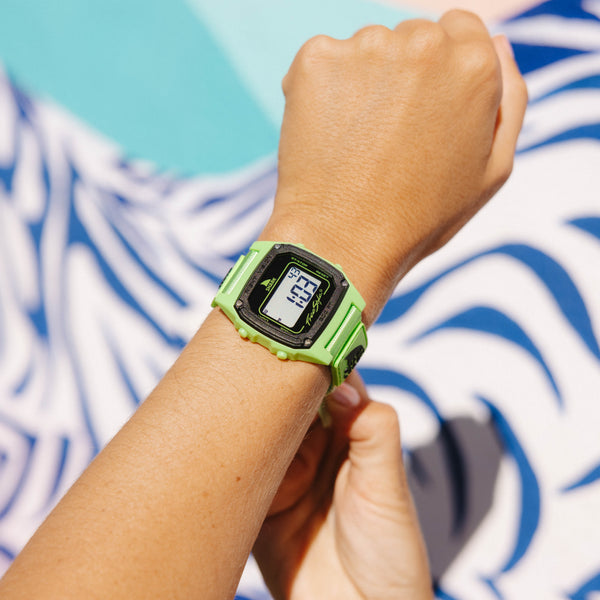 Person wearing a green digital watch with a blue and white patterned background
