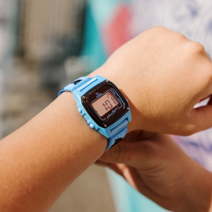 Digital watch with a blue strap on a wrist, blurred background