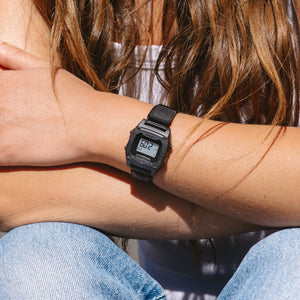 Person wearing a black digital watch on an arm.