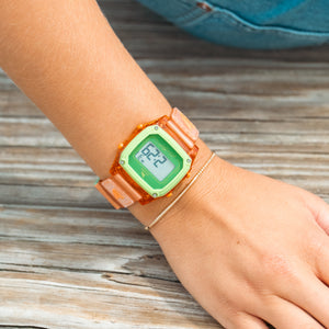 Orange digital watch on a wrist with a wooden background