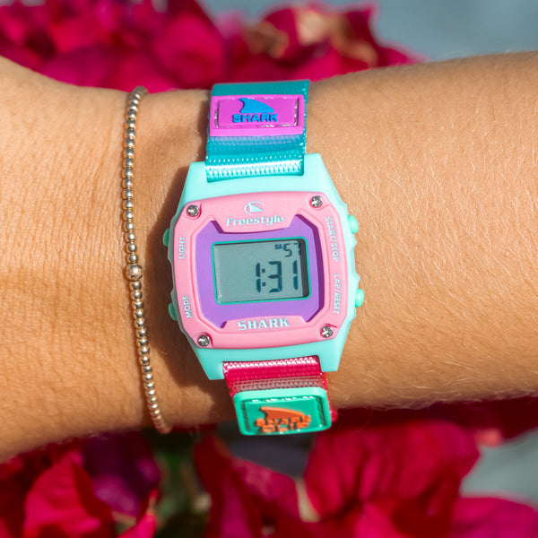 Colorful digital watch on a wrist with flowers in the background