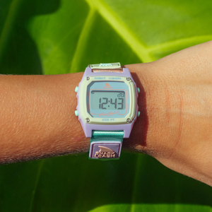 A SHARK CLASSIC LEASH MINT POP Freestyle watch is worn on a wrist against a green leaf background.