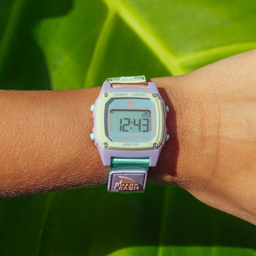 A SHARK CLASSIC LEASH MINT POP Freestyle watch is worn on a wrist against a green leaf background.
