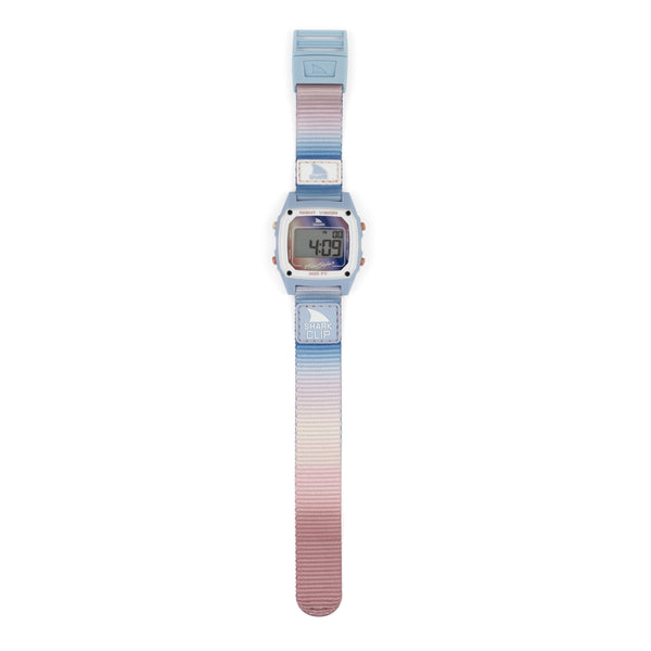 Freestyle Shark Clip watch laid flat, showing its blue-to-mauve gradient strap, signature clip closure, and digital display.