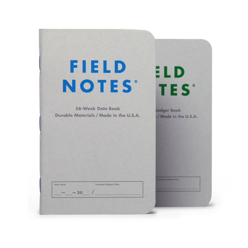 Two Freestyle USA 56 WEEK DATE BOOK & LEDGER BOOKS, gray with blue and green text, stand upright on a white background.