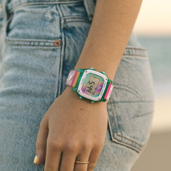 Person wearing a Freestyle SHARK CLASSIC CLIP PINK HORIZON watch and light blue jeans, standing outside.