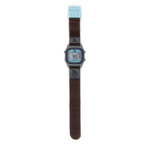 A Freestyle SHARK CLASSIC CLIP GREY/BLUE digital watch displays numbers on its square face with a grey and blue strap.