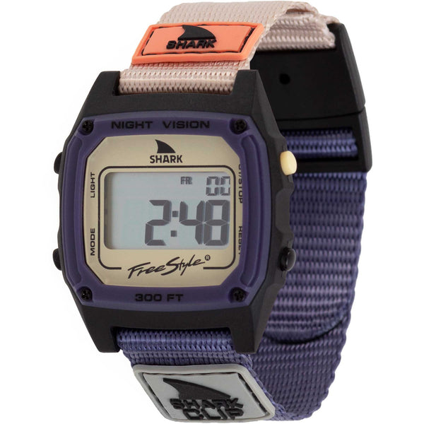 The Freestyle SHARK CLASSIC CLIP INDIGO TAN is a retro digital watch with a square face and nylon band. The display shows numbers on the screen.