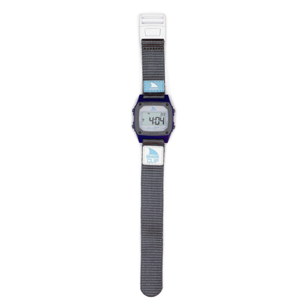 A Freestyle SHARK CLASSIC CLIP SEA LION watch with a gray fabric strap and rectangular face shows 4:04.