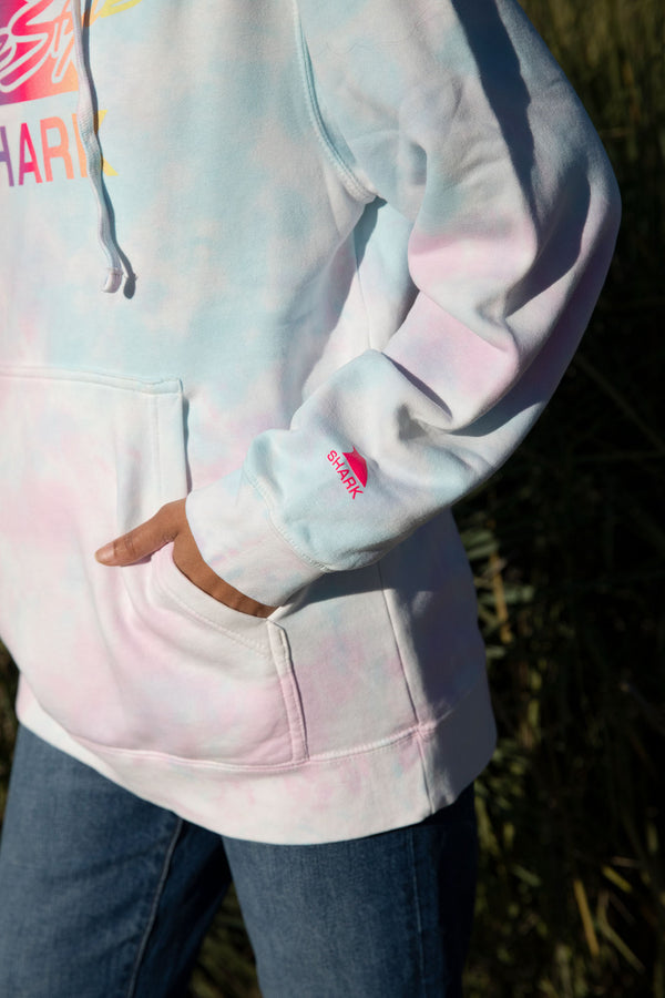 Person wearing Freestyles Unisex Cotton Candy Tie Dye Hoodie with hand in pocket, paired with jeans, standing outdoors.