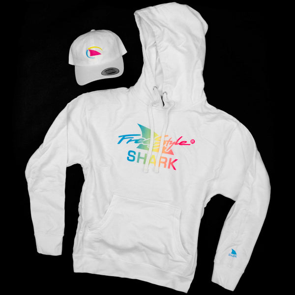 Flat lay of a white Freestyle Shark hoodie with a rainbow gradient logo and matching white Freestyle Dad Cap featuring a neon shark fin embroidery, displayed on a black background.
